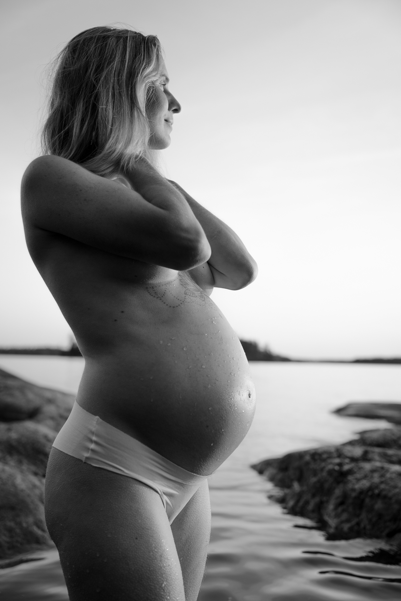 Svartvit bild på gravid kvinna vid vattnet.