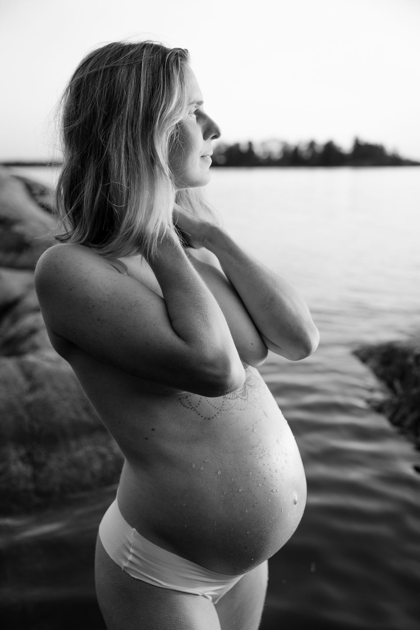 Svartvit bild på gravid kvinna vid vattnet.