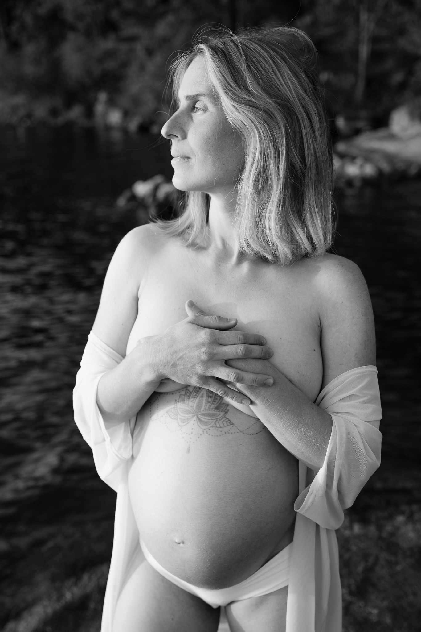 Svartvit bild på gravid kvinna vid vattnet.