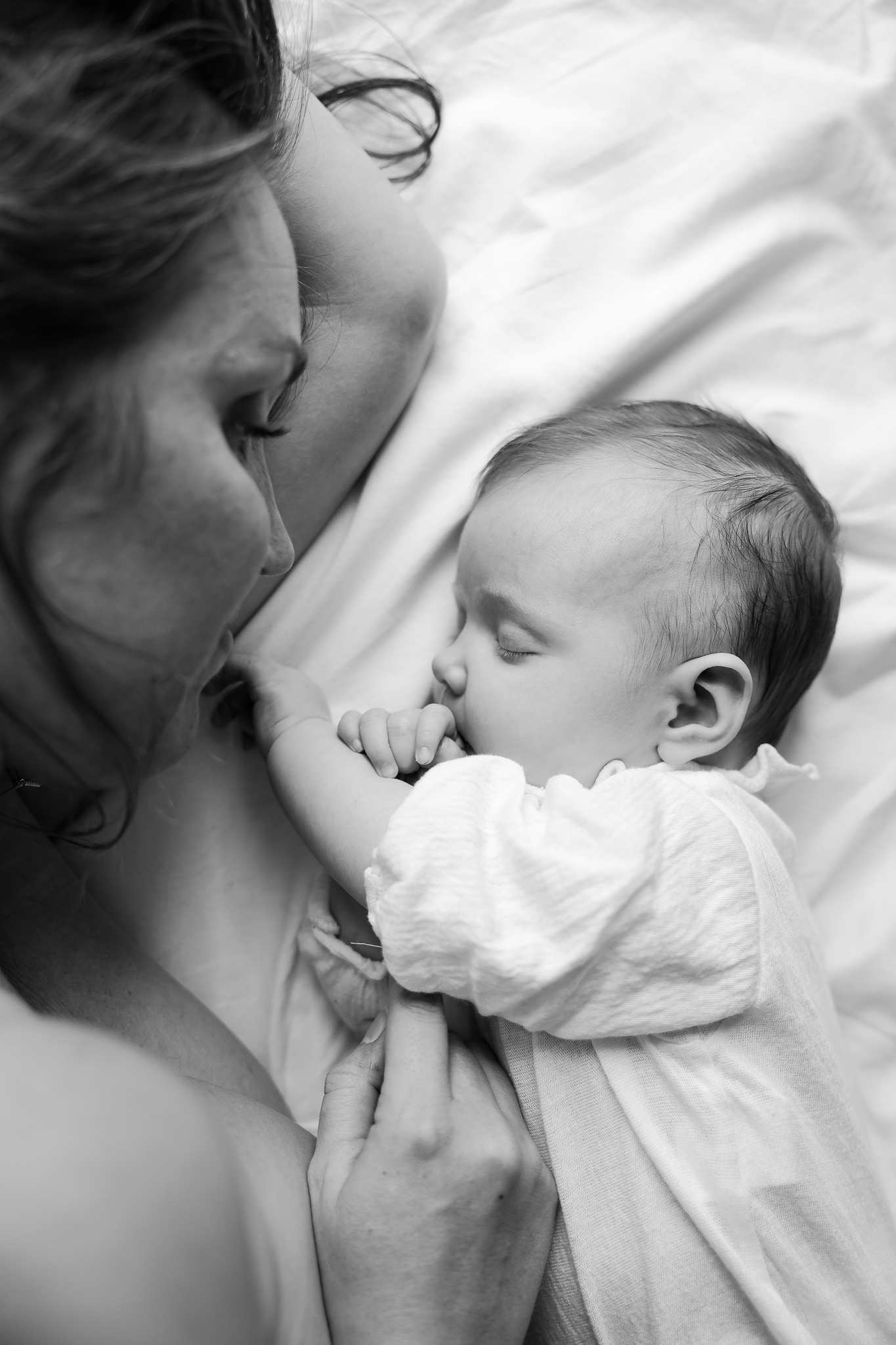 Svartvit bild på en mamma myser på en filt tillsammans med sin bebis.