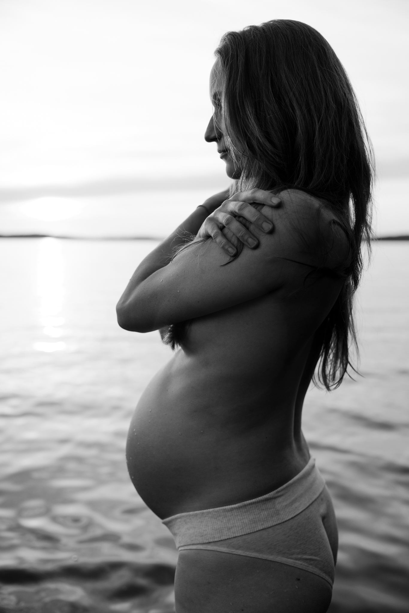 En gravid kvinna står vid vattnet.