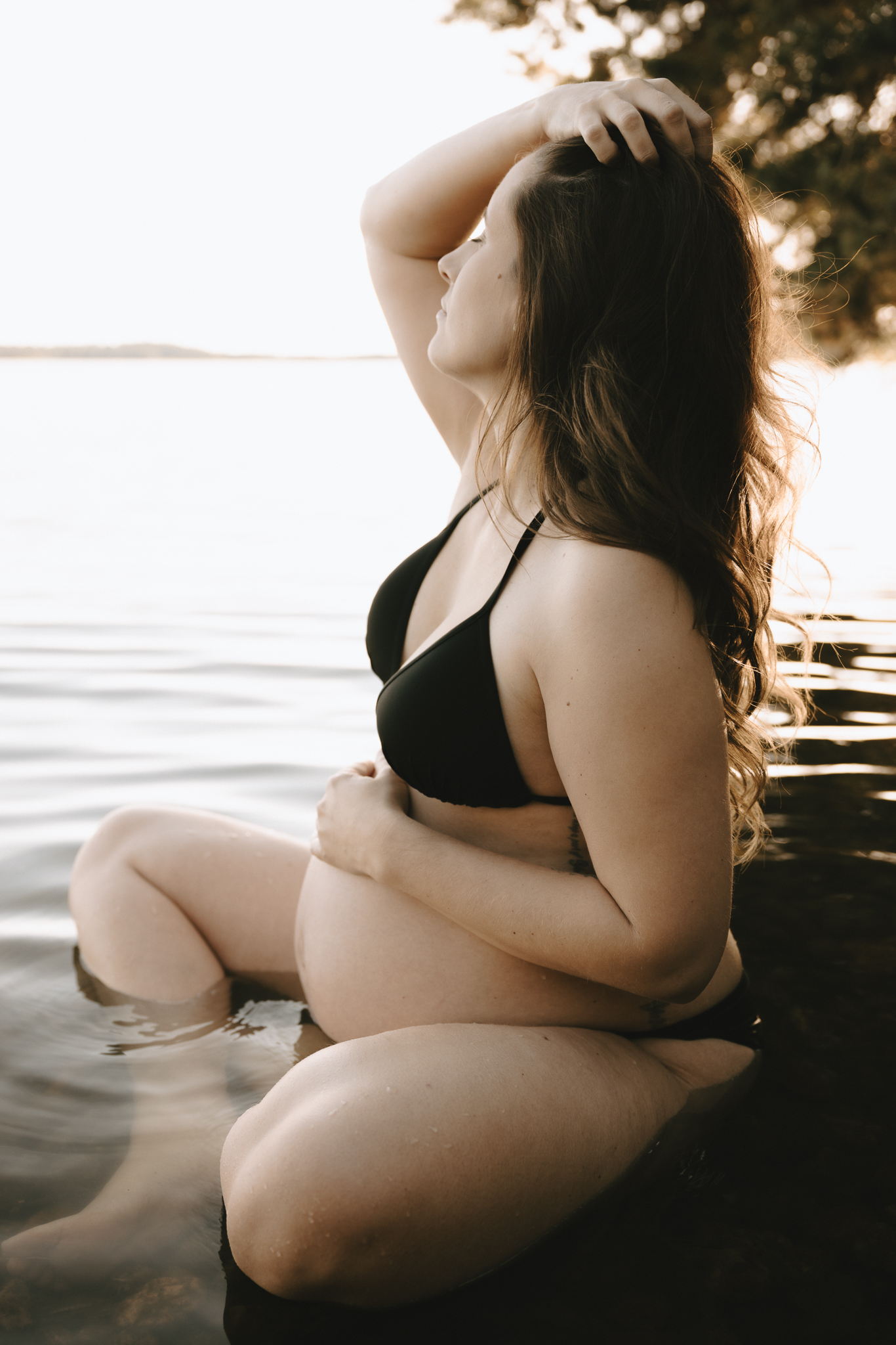 En gravid kvinna sitter i vattnet.