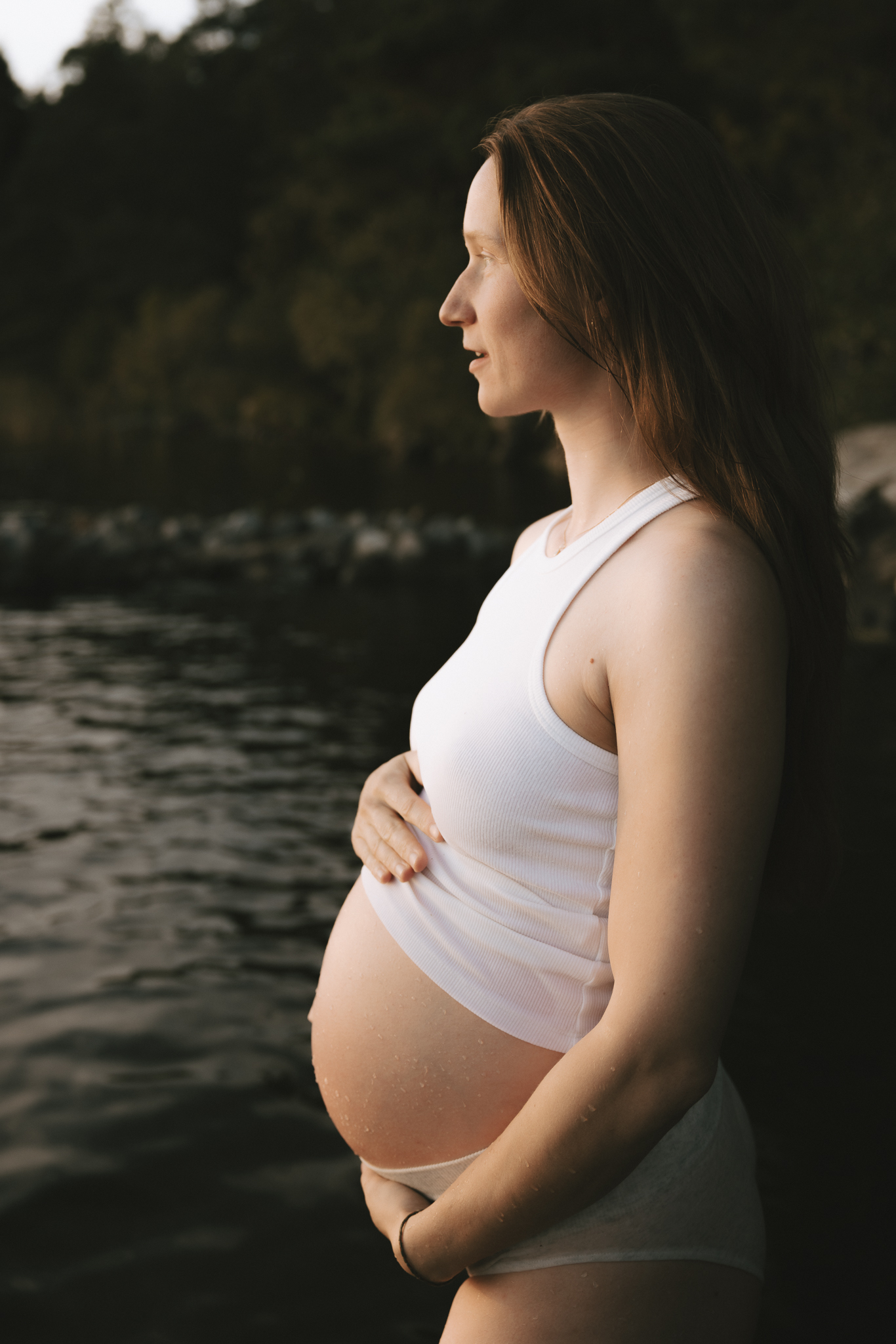 En gravid kvinna står i vattnet.