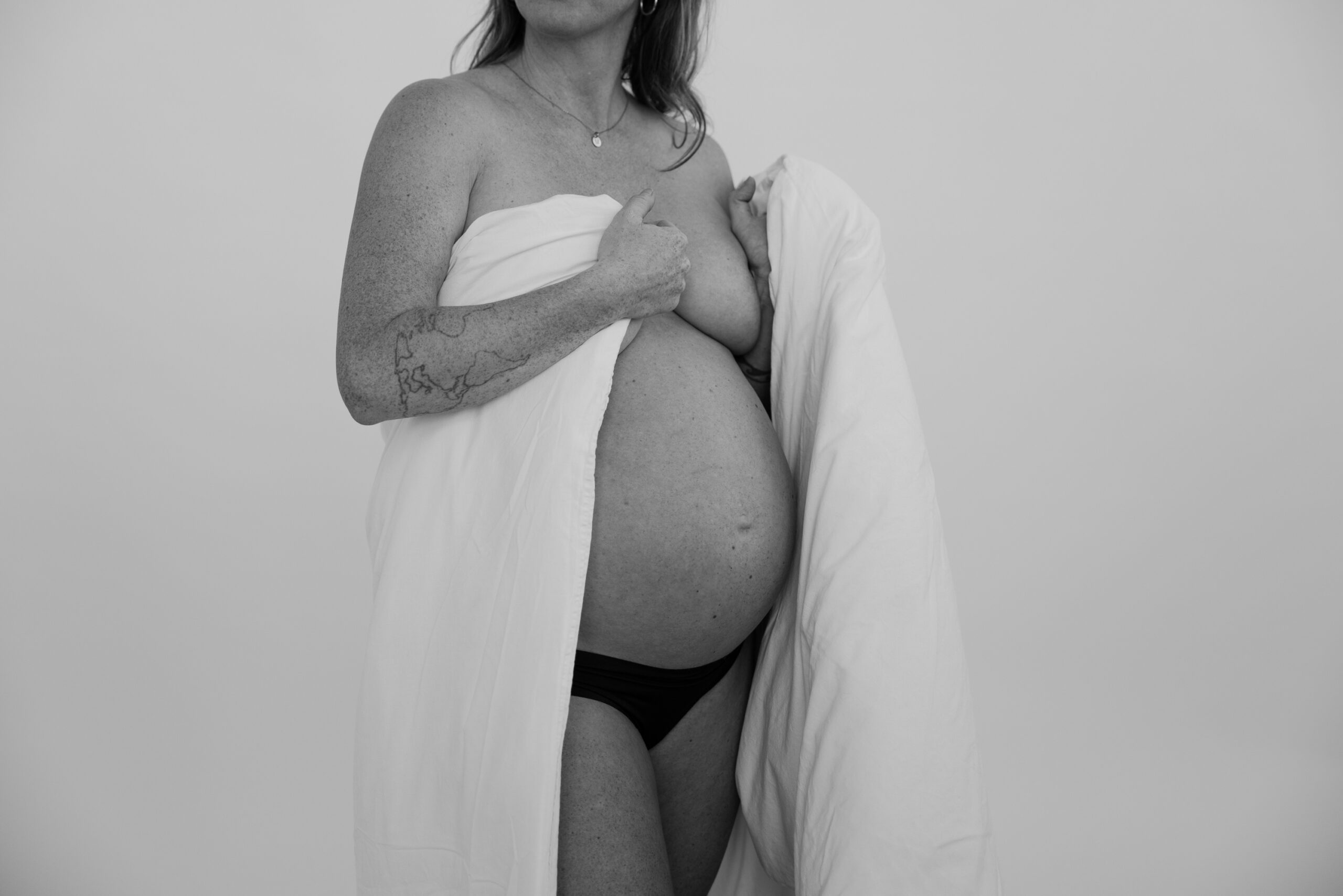 Svartvit bild på gravid kvinna i studio.